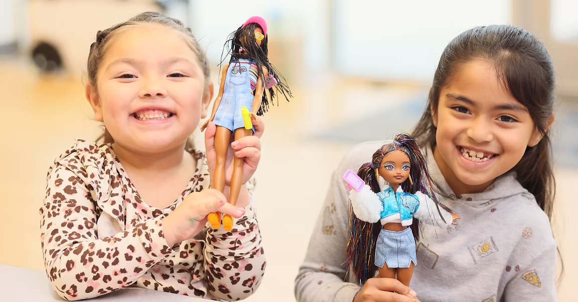 Children smiling with dolls received through community support